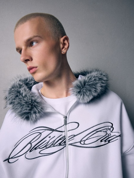 Biała rozpinana bluza z napisem i kapturem ze sztucznym futerkiem