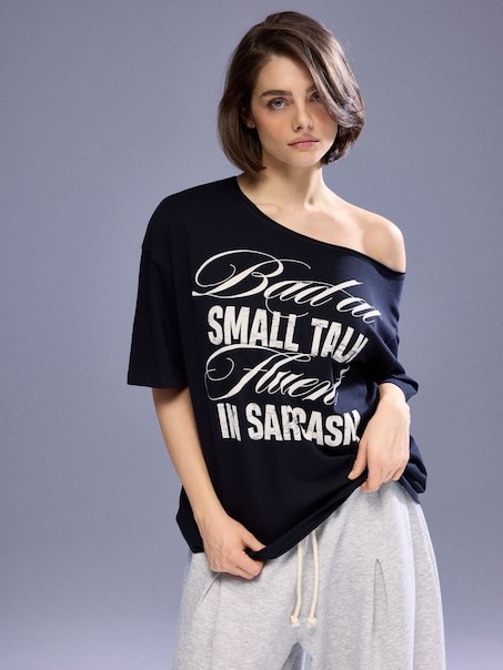 Czarna koszulka z napisem Bad at Small Talk Fluent in Sarcasm i opuszczonym ramieniem