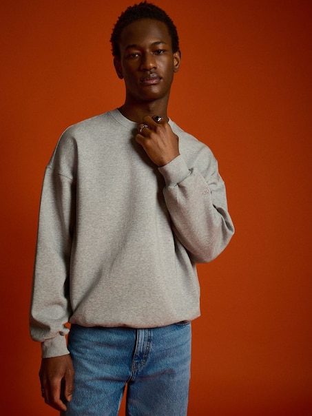 Jasnoszara bluza crewneck z małym haftem na rękawie