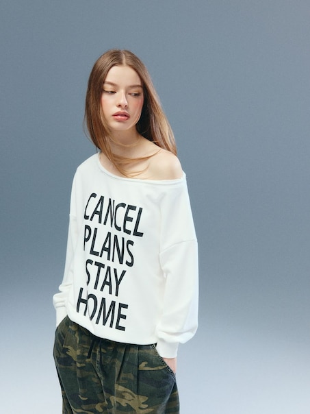 Kremowa bluza na jedno ramię z napisem Cancel Plans Stay Home